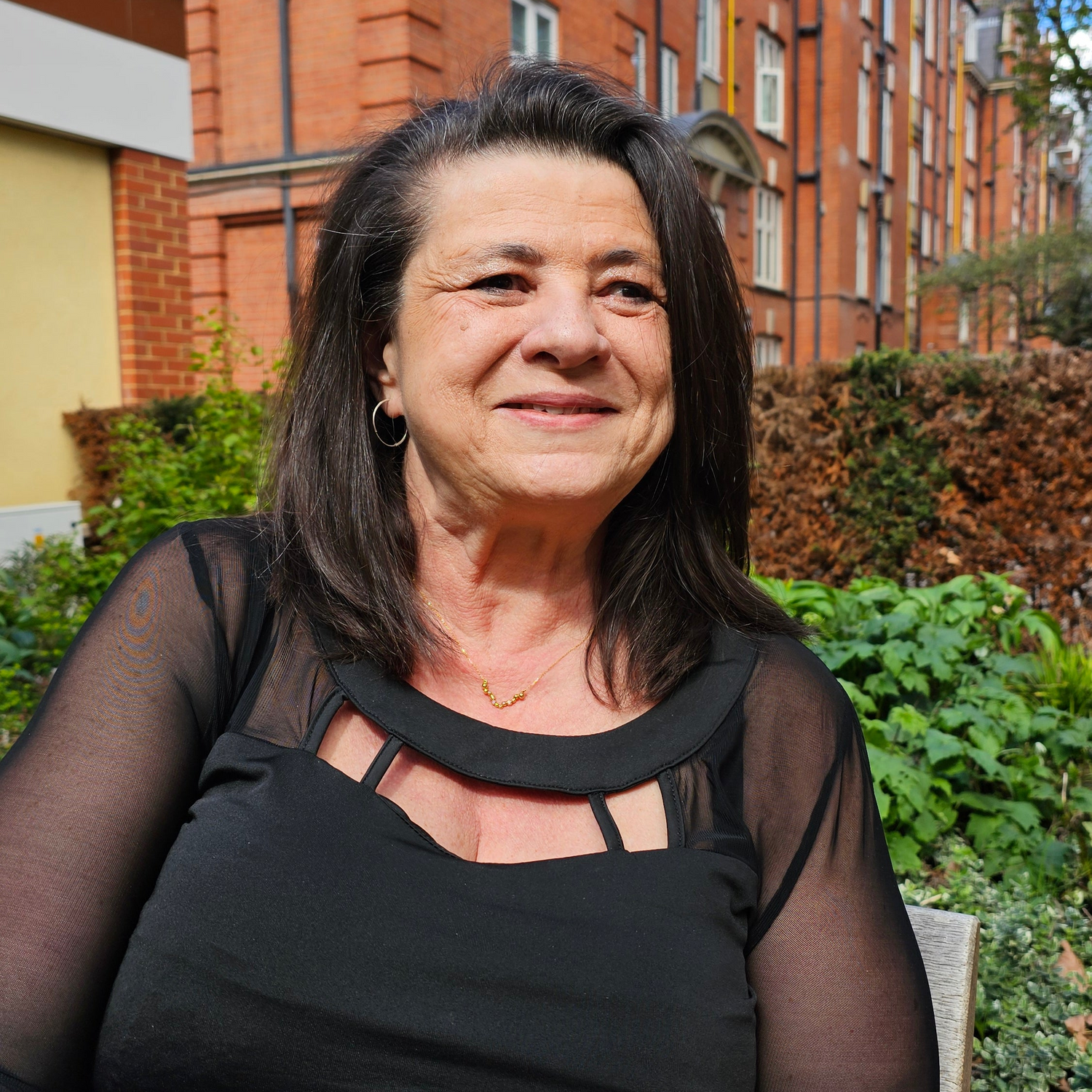 Woman standing in front of a brick building with greenery