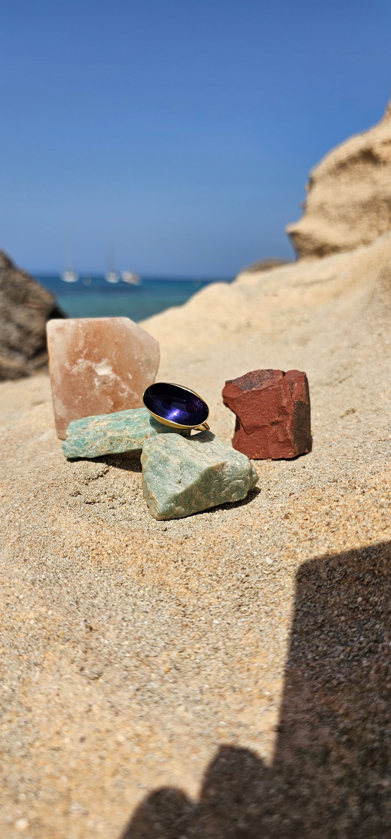 Decorative stones on a reef with blue-enameled gold ring, on a light blue sky on the background.